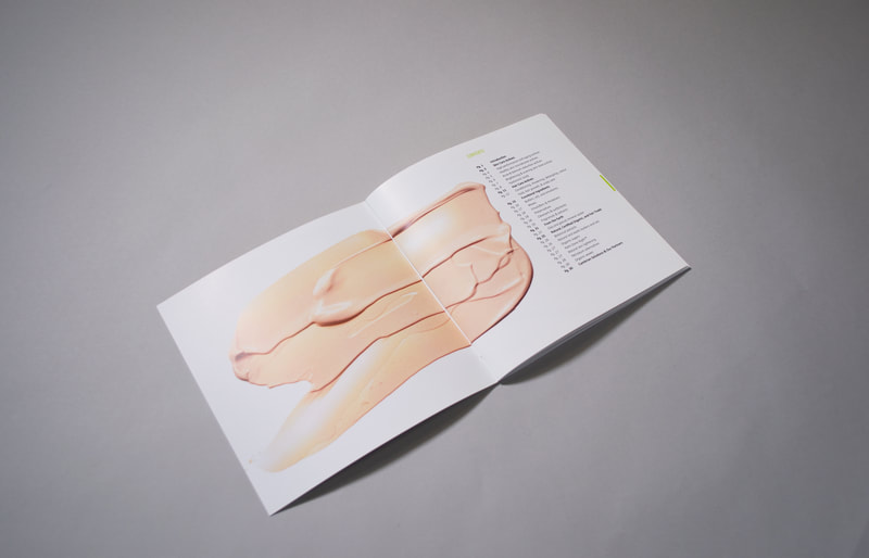 Photograph of the Table of Contents spread of a brochure which features a photograph of a swatch of foundation makeup in a light, peachy-pale skin colour.