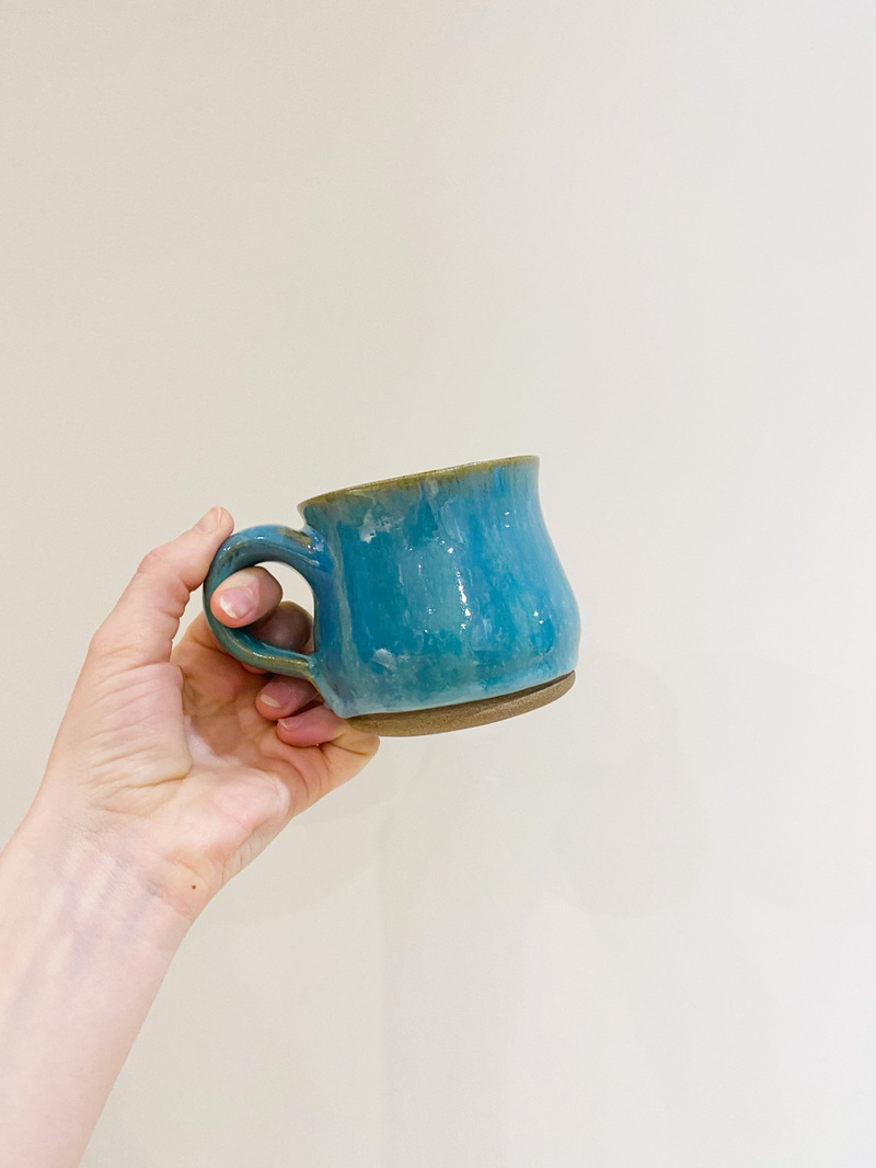 A squat turquoise mug with blue melting glaze